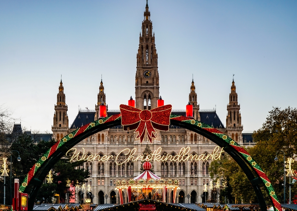 The welcome sign to the Vienna Christmas market is bright with reds, yellows and greens. A carousel sits in the middle of the town square, noting that this is one of the places in Europe that are even better in winter. 