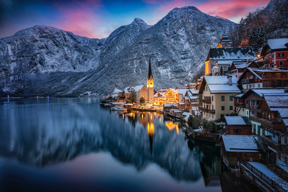 Hallstatt is one of those places in Europe that are even better in winter: this photo shows its pink sky in the back of snowy mountains, and its town set a glow over a lake with warm lights. 