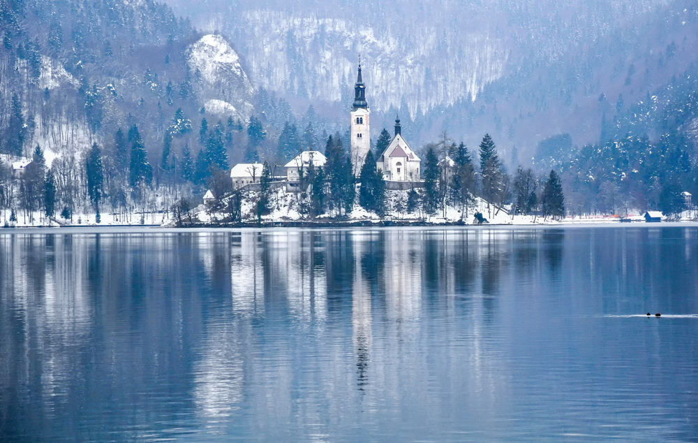 In the middle of Lake Bed sits an island with a little church and town: it is covered in white snow, and it reflects into the cool water of the lake. 