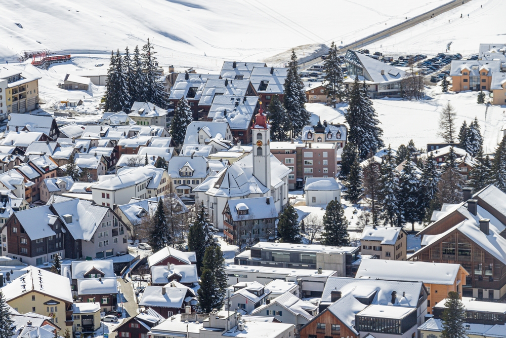 A sky-shot shows a European city, one of the places in Europe that are even better in winter, topped with white snow, green fir trees, and more. 