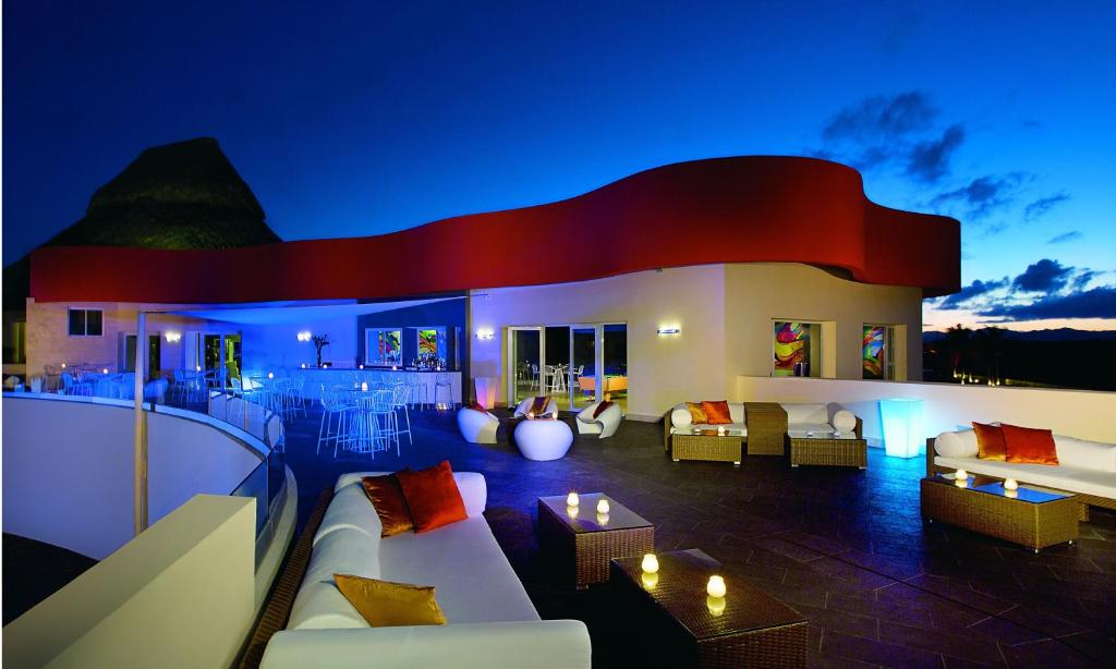 Rooftop bar with unusual shaped building. There are loungers on the deck and a mountain can be seen in the distance. 