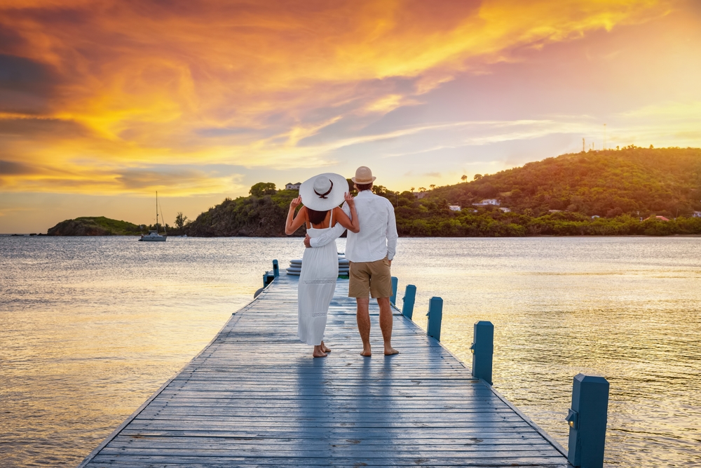 a couple at sunset on a dock overlooking the ocean and hills