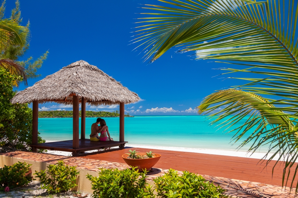 a couple sitting under a cabanas overlooking the ocean at their resort in the Caribbean Honeymoon