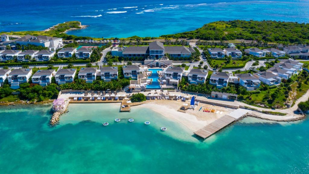 Birdseye view of a resort with a large swimming pool and blue houses. 