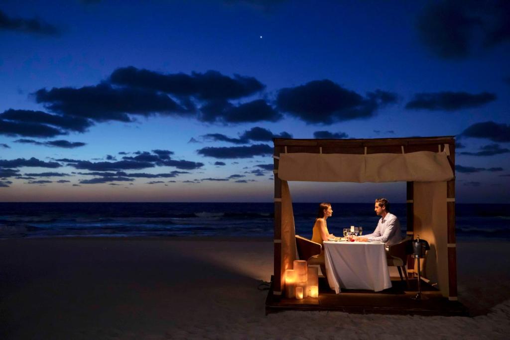 Dining table outside with couple having dinner buy the ocean. 