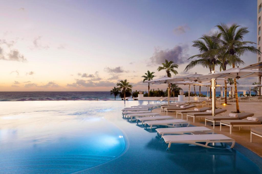 Wonderful pool surrounded by loungers and trees looking out over the ocean.