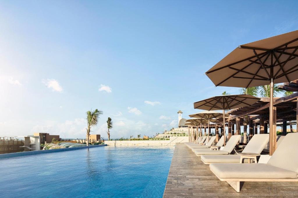 Pool in resort surrounded by loungers and umbrellas. 