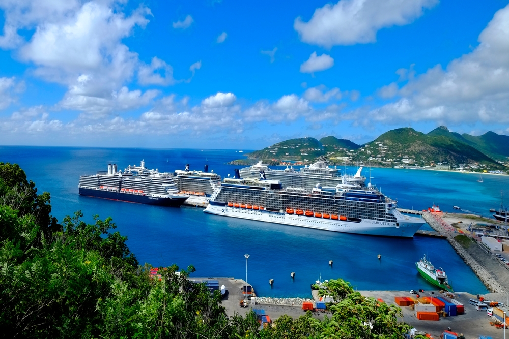 A cruise ship docks at a port in Holland, the blue waters and entry port allowing guests to get off and explore the green land surrounding the docks. 