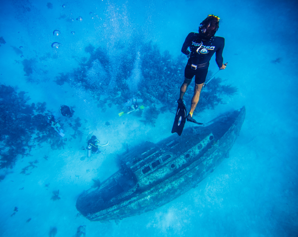 A guest explores a day excursion of a scuba diving experience near a ship wreck, which is a plus when looking at  all inclusives vs cruises.