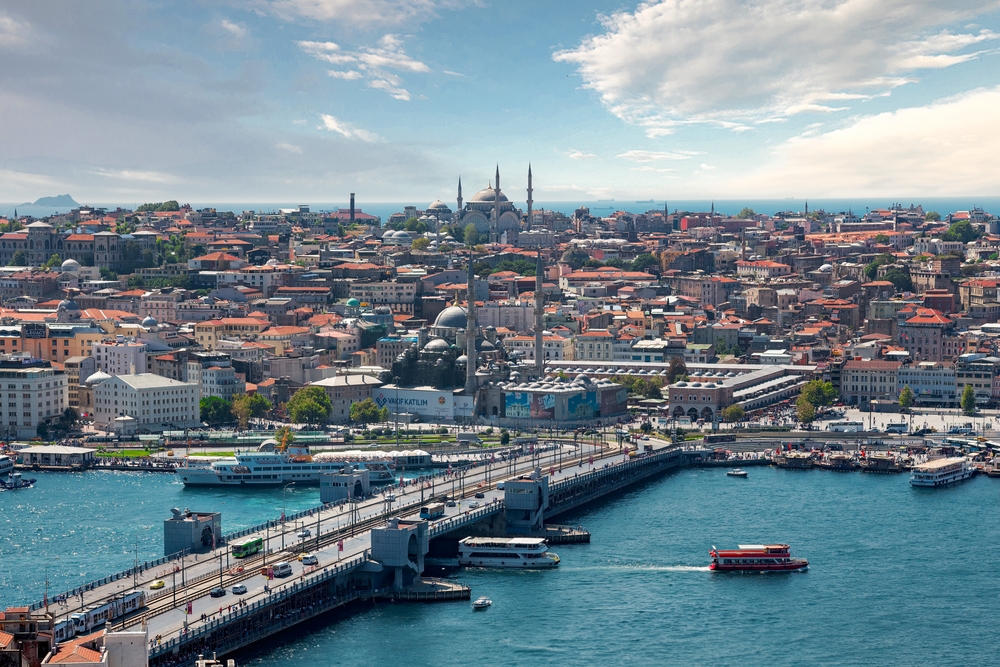 a photo of a bridge over water leading to the city of istanbul, the hagia sophia is in the background 