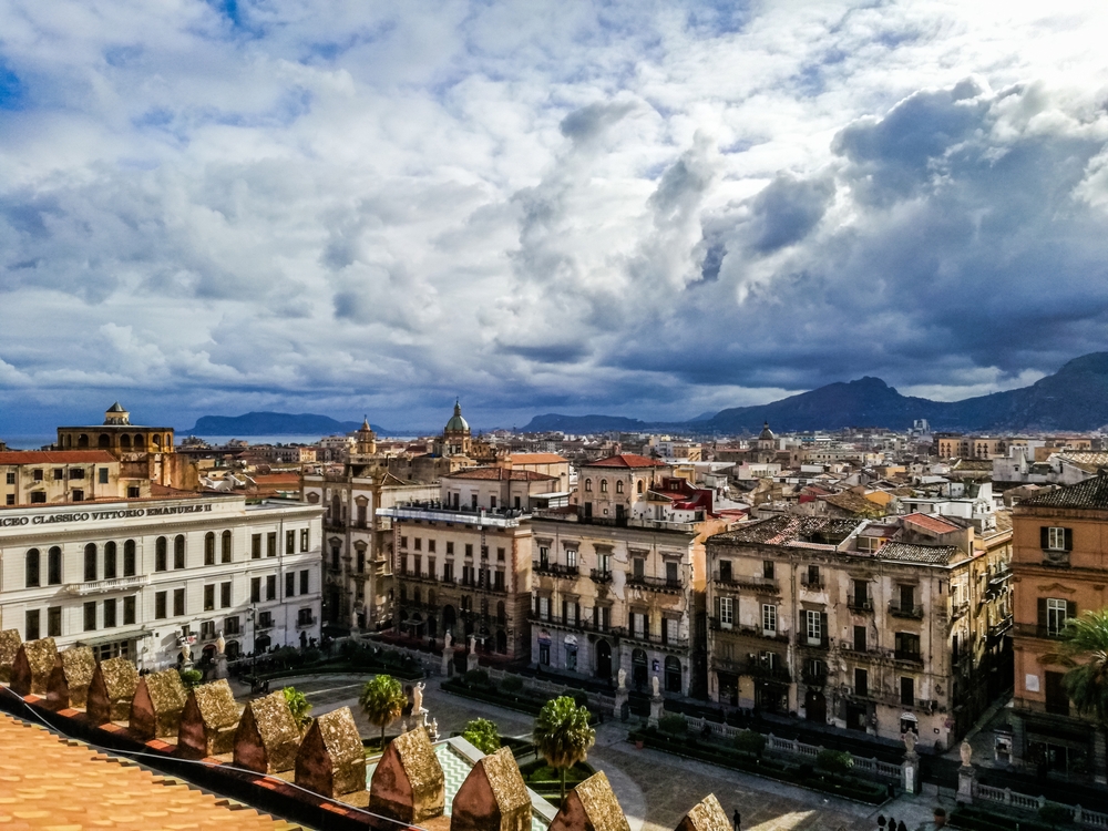 mountains in the background on a cloudy day, city streets and buildings in the foreground , one of the best places to visit in europe in january 