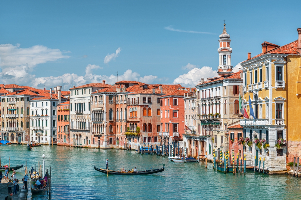 one of  the best places to visit in europe in january, venice italy canal with a gondala floating in the middle, buildings to the right of the canal 