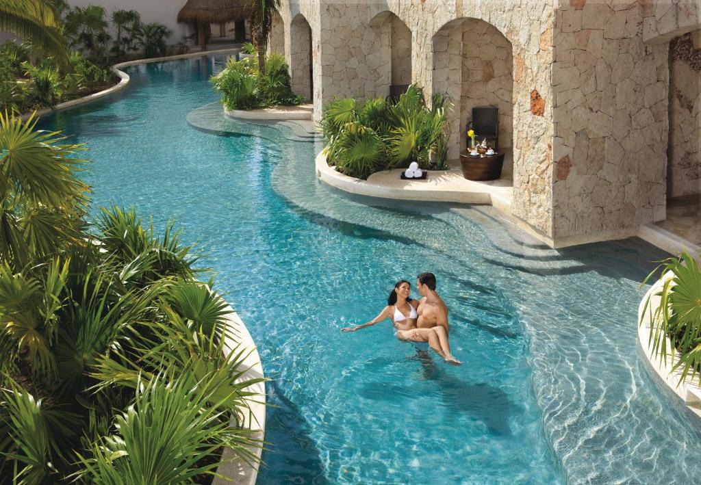 Man and women in the water outside a swim up hotel room. One of the adults-only all inclusive resorts in the Caribbean 