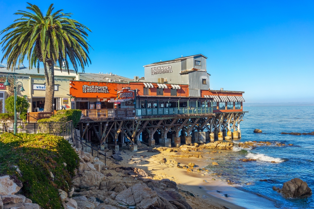 the Fish Hopper restaurant partially suspended over the water with a small beach to the right in Monterey California