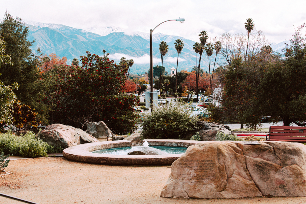 a small fountain in downtown Ojai, California with snow capped mountains in the distance