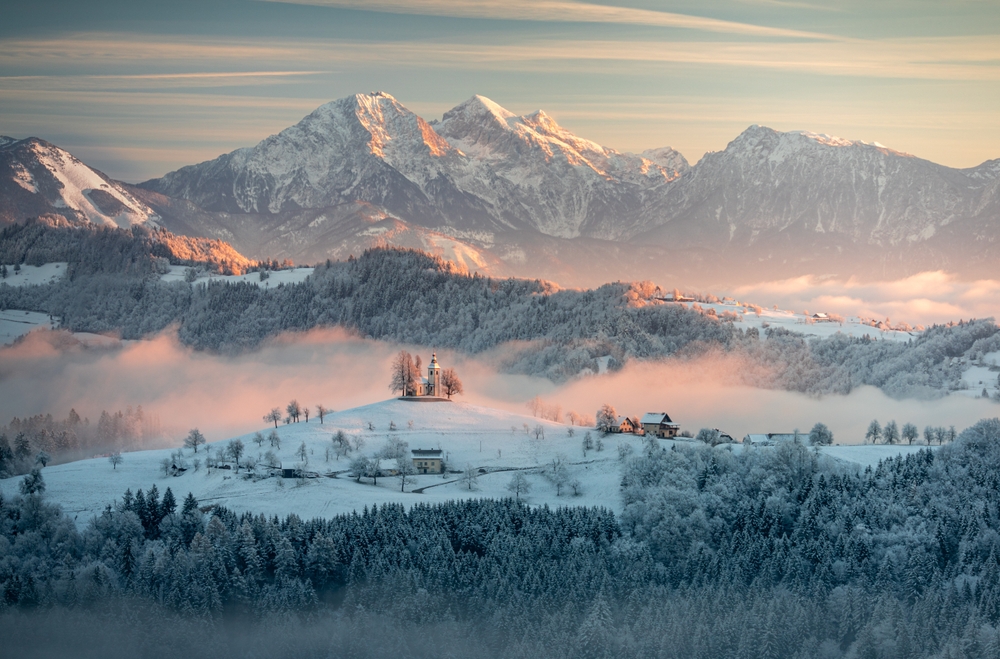 A foggy snowy sunrise in a countryside landscape with the church of Sveti Tomaz, Slovenia. One of the underrated countries in Europe.