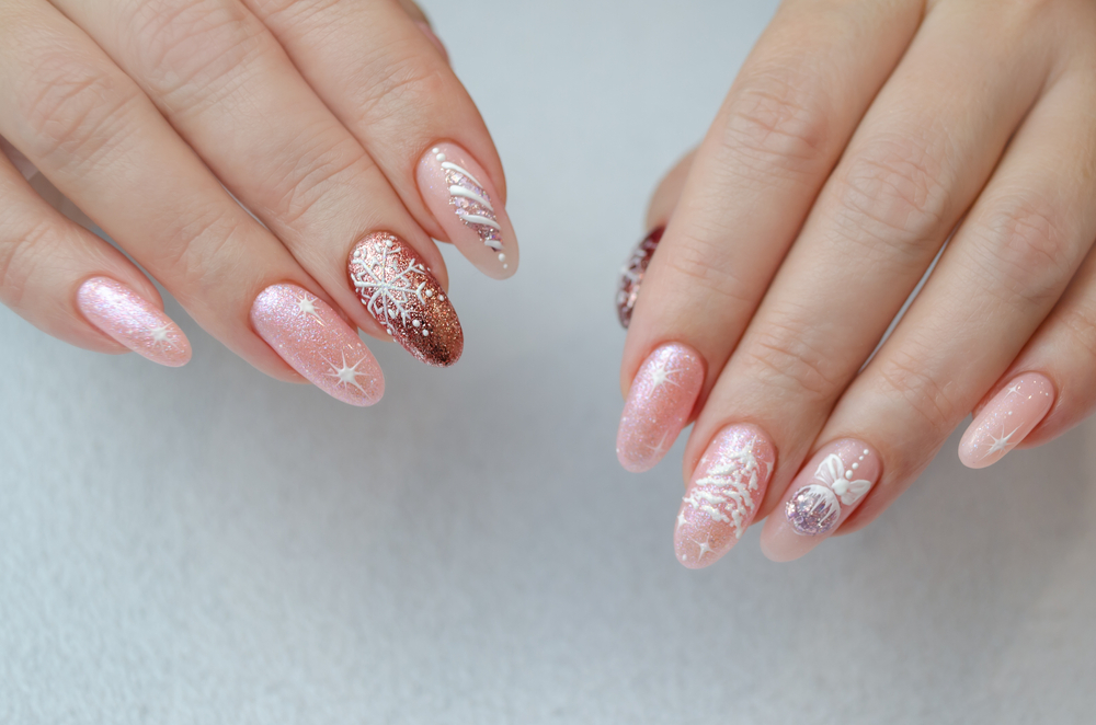 The hand of a young woman with a pink manicure and design for the New Year and Christmas. Festive Christmas Nail Ideas for winter vacations