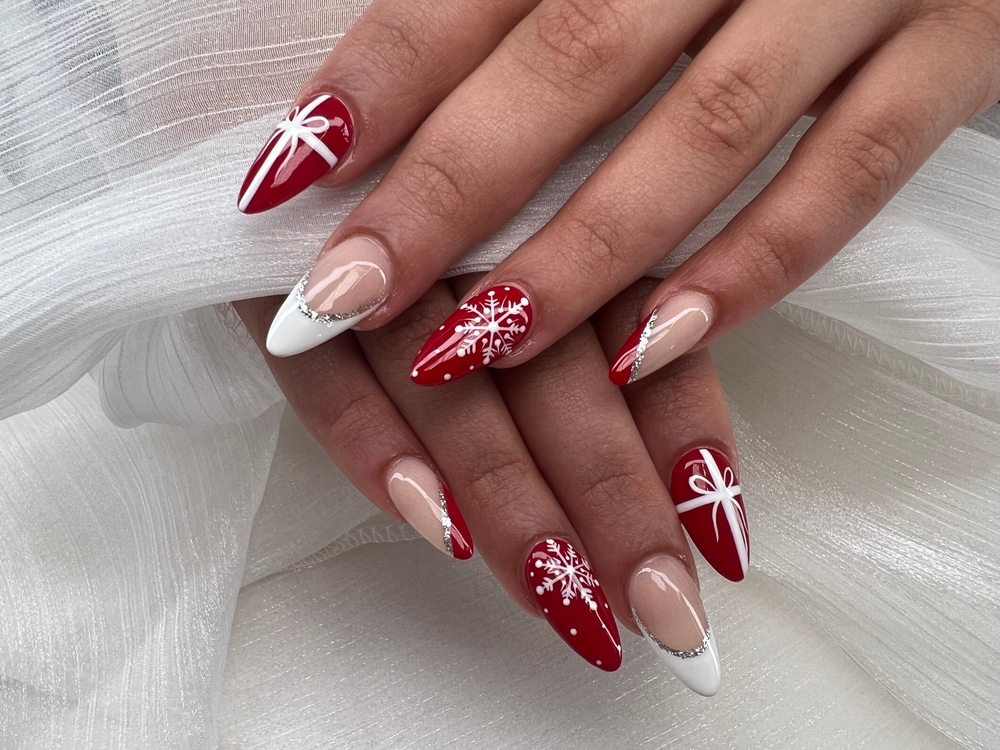 Festive Nail Designs to Spark Holiday Joy, in red and white gel nail polish. The nails have snowflakes on. 