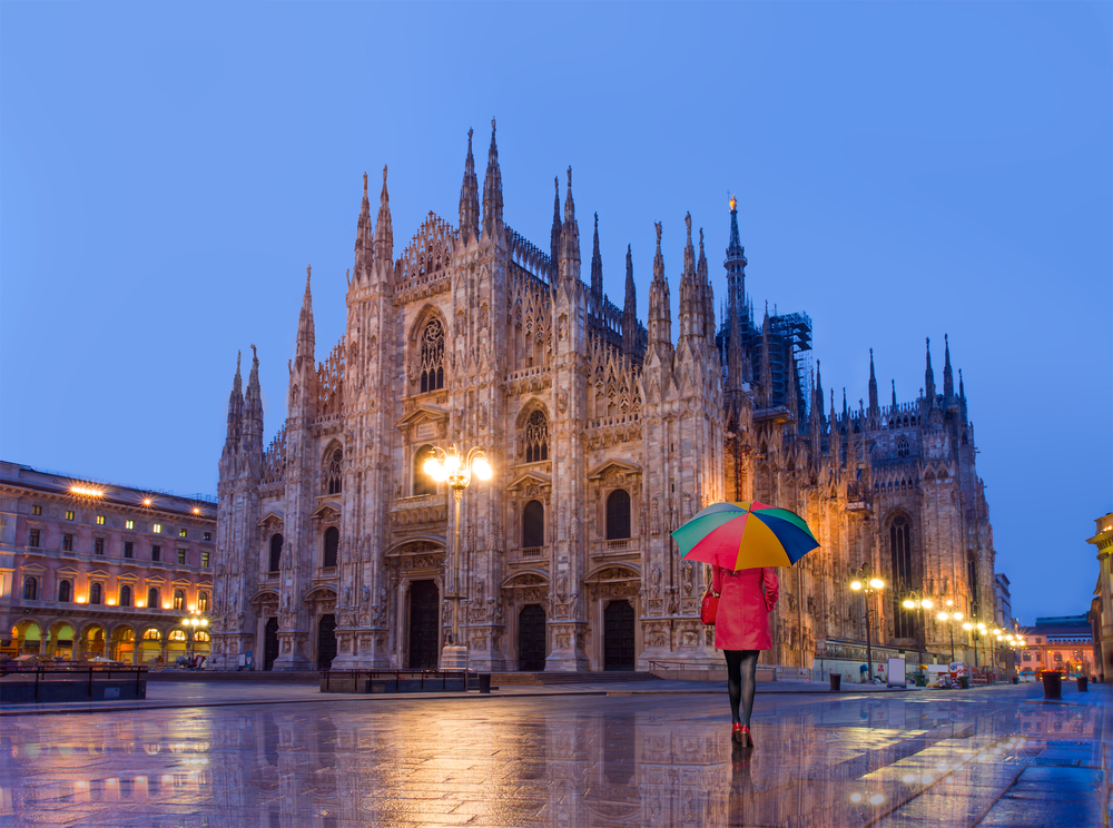 woman walking in pink outfit with umbrella in milan italy during the rain 