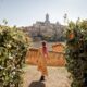 woman standing in tuscany italy wearing a brown dress surrounded by vineyards