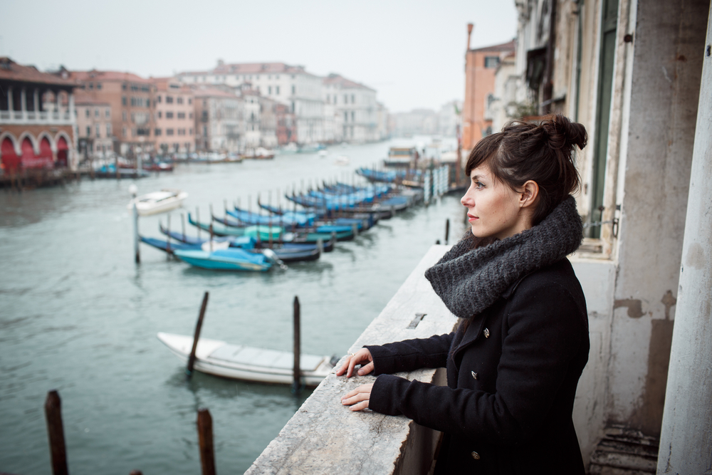 woman in a black outfit during winter in venice italy looking over the canals