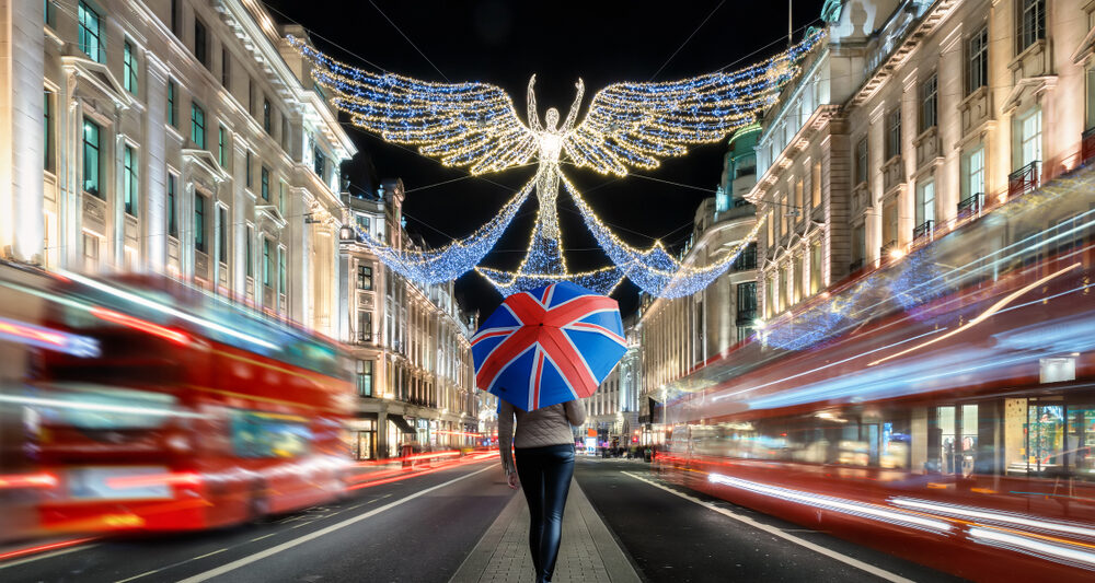 woman standing with a british flag umbrella on the streets of london in december