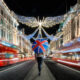 woman standing with a british flag umbrella on the streets of london in december