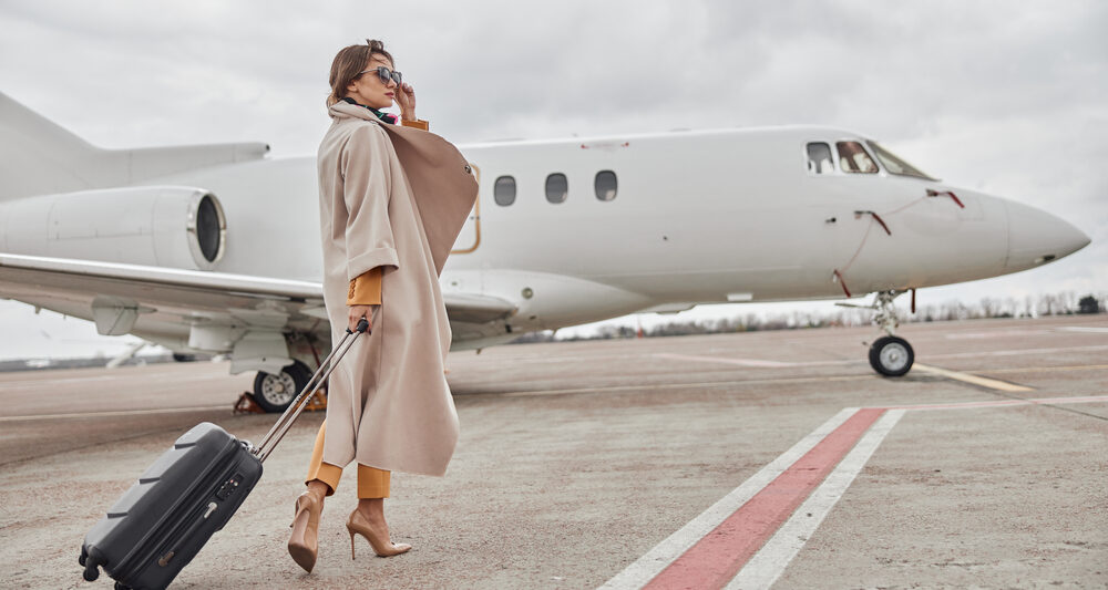 woman wearing long coat standing outside of airplane