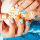 woman wearing nailpolish painted for the beach holding a shell