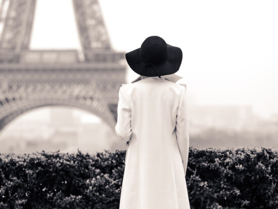 a girl in long coat facing Eiffel Tower