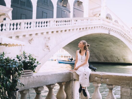 woman sitting in venice wearing a white dress holding a camera