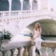 woman sitting in venice wearing a white dress holding a camera