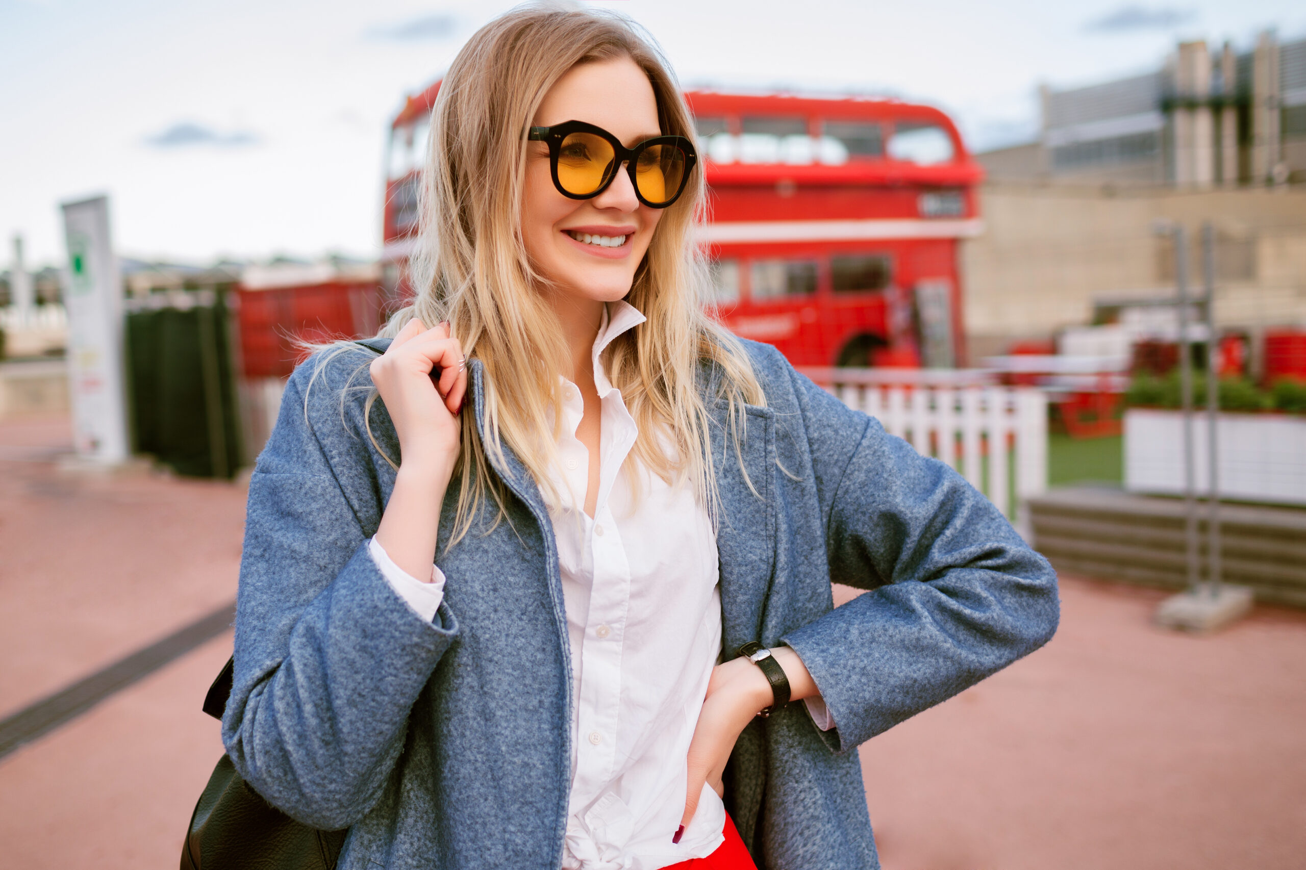 Women in jacket by London bus. Article is about  what to wear in London in spring. 