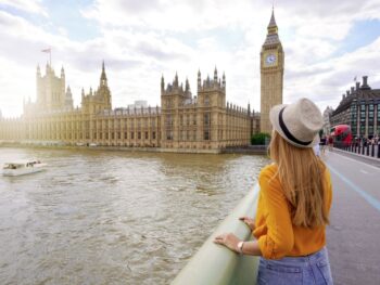 woman in yellow sweater standing in front of big ben in london in spring