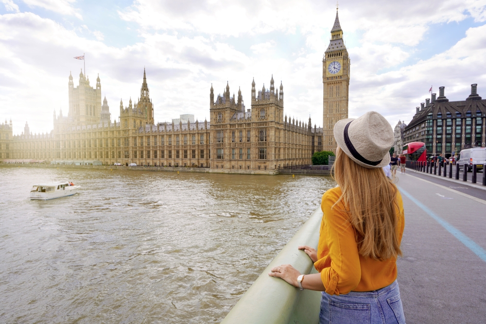 girl with hat on in front of big ben. 