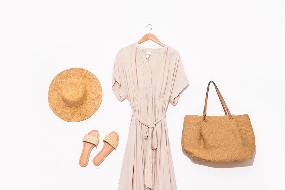 a linen dress, straw hat, sandals and bag shows an example of what to wear to Italy in Summer