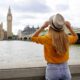 woman standing in front of big ben during london in summer wearing an orange top and blue jeans