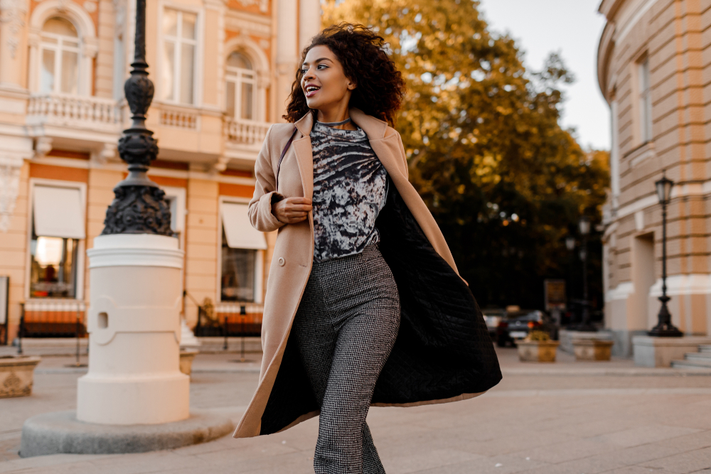 Woman walking with long, beige coat over a chic Paris outfit in October.