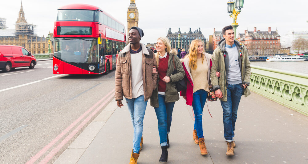 A group of friends in jeans, ankle boots, jackets and sweaters walk down the city's streets, not worrying about what to wear in London in February, enjoying the Double Deckers behind them and Big Ben in the background.