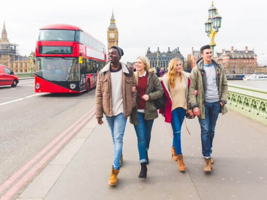 A group of friends in jeans, ankle boots, jackets and sweaters walk down the city's streets, not worrying about what to wear in London in February, enjoying the Double Deckers behind them and Big Ben in the background.