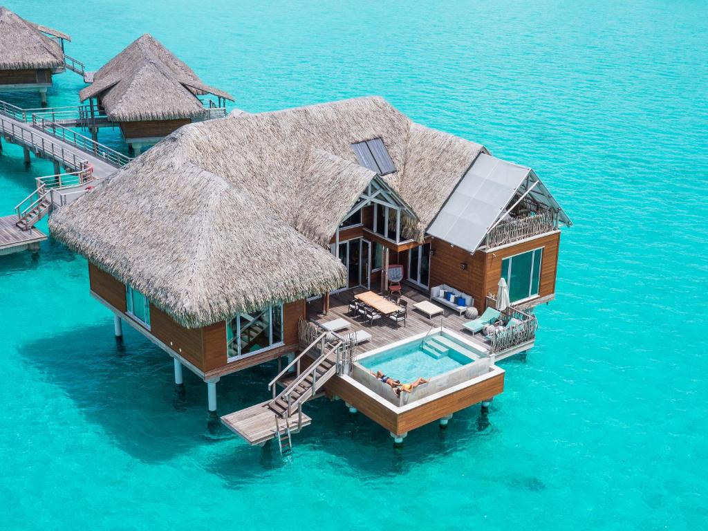 Shot of a water bungalow from over the top showing people in their private pool. 