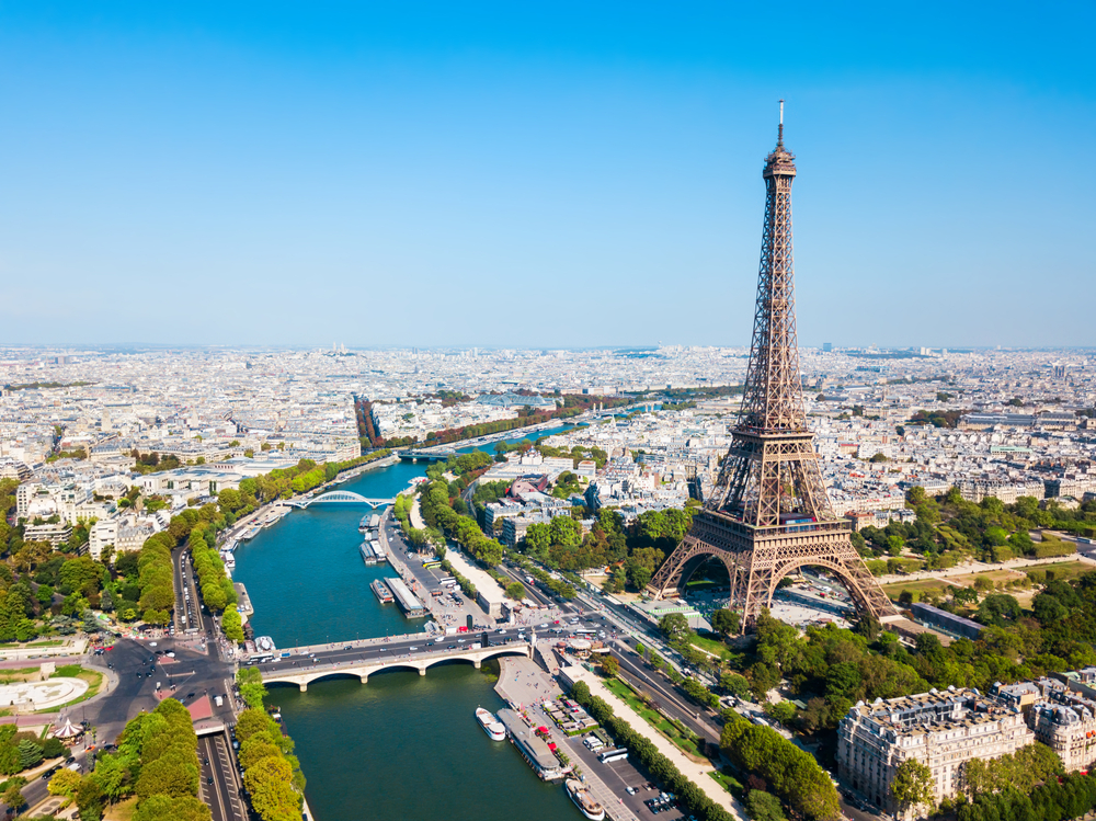 an Ariel view of Eiffel Tower with the Siene River and the rest of the city in the background