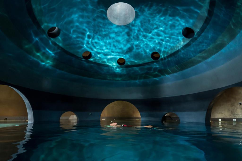 round spa pool with someone floating in it. The water is reflected on the ceiling.  This is one of the best spa resorts in Europe. 