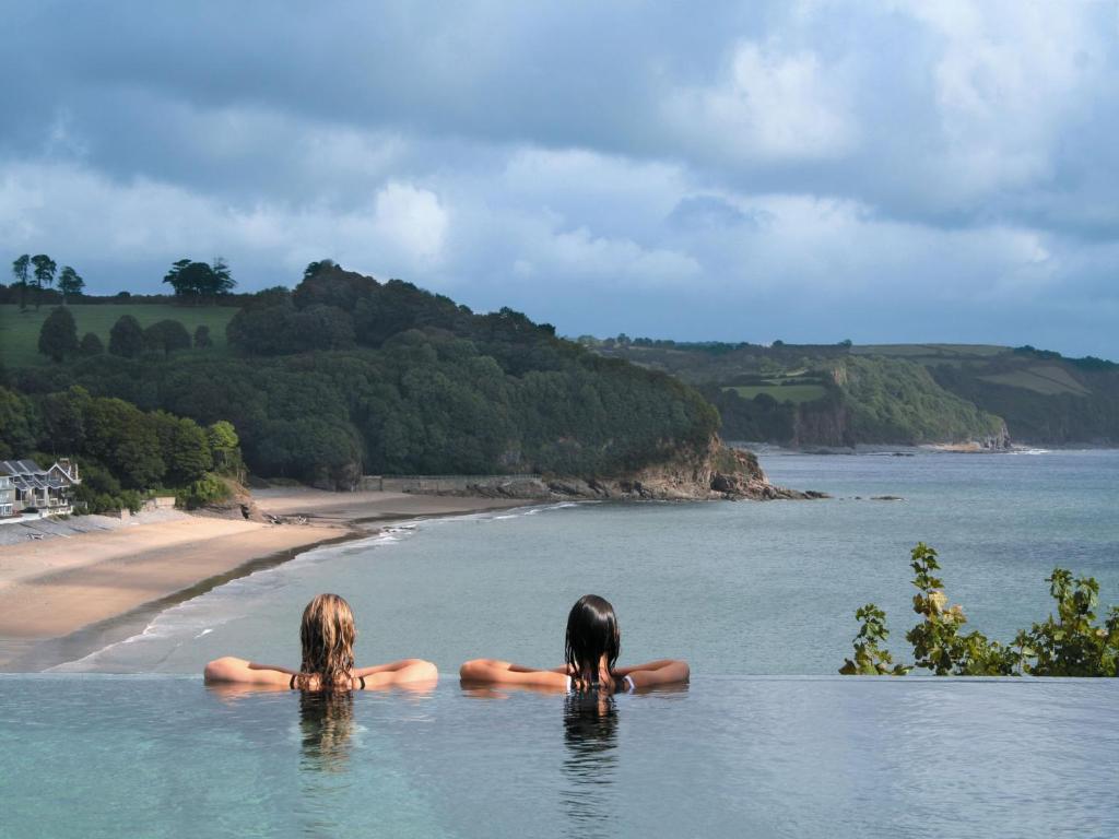 Two women in a pool looking over the ocean and hills. One of the best spa resorts in Europe