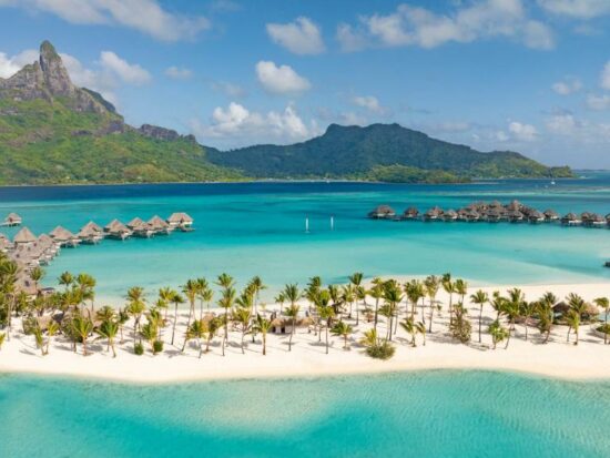 resort in bora bora with soft white sand and overwater bungalows in the background and a mountain