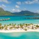 resort in bora bora with soft white sand and overwater bungalows in the background and a mountain