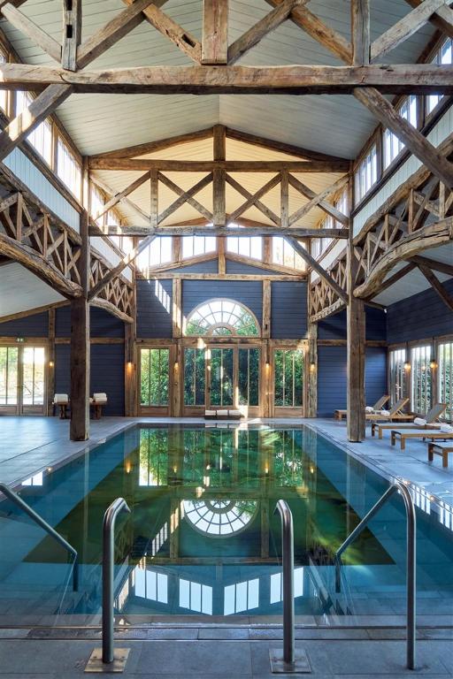 A pool within a barn with a large window. It is one of the best spa resorts in Europe