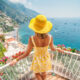 a woman in yellow sunhat and yellow dress standing overlooking Amalfi Coast