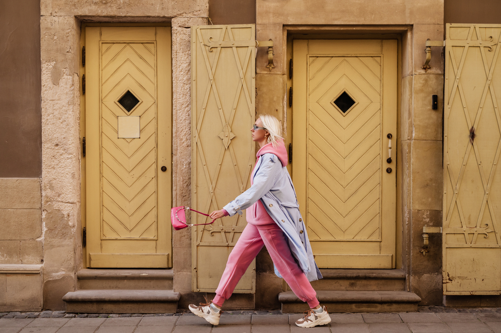 Sometimes when wondering what to wear in Europe in spring you still have to think warm: like this woman who wears a pink sweat shirt under a purple trench coat and with sneakers as she walks down the street. 