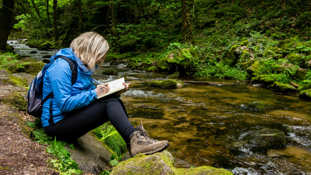 If you're hiking then what to wear in Europe in spring looks a little different: this woman sits on the edge of the hiking trail with boots, cargo pants and a weatherproof jacket. 